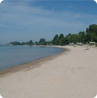 A beach dotted with the occasional person enjoying the warm sun.